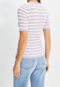 Violett-weiß gestreiftes Strickoberteil mit kurzen Ärmeln, gerippter Textur, rundem Ausschnitt, kombiniert mit hellblauen Jeans.