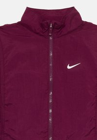 Fato de fecho em bordeaux com colarinho alto e logótipo branco da Nike em swoosh no lado direito do peito.