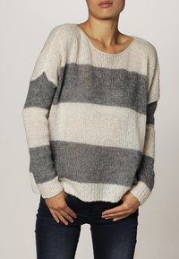 Randig tröja i mjukt stickat material, med breda grå och off-white ränder. Löst sittande passform med rundad halsringning och ribbade ärmslut.