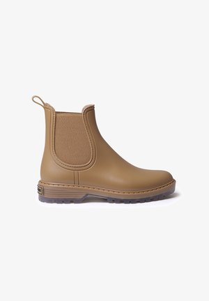 Tan ankelboots tillverkade av gummi med elastiska sidopaneler, texturerad yta, dragflik och en hållbar mönstrad sula för bra grepp.