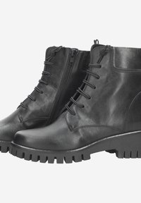 Bottines en cuir noir avec un bout rond, un laçage à l'avant, une fermeture éclair sur le côté et une semelle robuste avec un motif de bande de roulement prononcé.