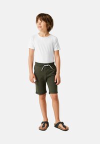 White short-sleeve t-shirt, dark green knee-length shorts with foldable hem and drawstring, paired with black flip-flops.