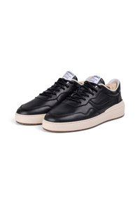 Sorte lærersneakers med polstret tunge og snørredesign. Har en kraftig kremfarget mellomsole og teksturert gummisåle.