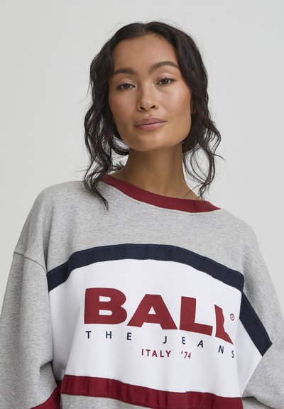 Sweatshirt gris oversize avec un col rond, arborant des rayures rouges et bleu marine ainsi qu'un logo "BALL" audacieux en bordeaux sur la poitrine.