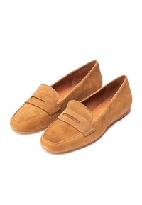 Lichtbruine suède loafers met een platte zool, voorzien van een ronde neus en een gestikte accentband aan de voorkant. Gladde textuur en minimale details.