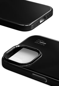 Czarny futerał na smartfon z błyszczącym wykończeniem, precyzyjnymi wycięciami na porty oraz prostokątnym otworem na obiektyw aparatu z detalem brandingowym.