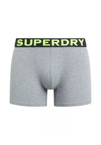 Bóxer gris con una textura suave y un ajuste ajustado, con una cinturilla negra que lleva la inscripción "SUPERDRY" en verde.