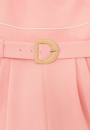 Vaaleanpunainen kangasvyö, jossa on kudottu D-kirjaimen muotoinen solki, kiinnitetty laskostetun vaatteen ympärille.