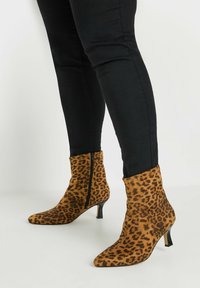 Botines de estampado de leopardo hechos de un tejido suave, con punta afilada y un tacón negro delgado, y cremallera lateral para facilitar su uso.