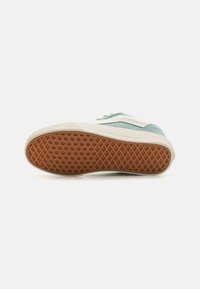 Light blue and white sneaker featuring a rubber sole with a waffle pattern, textured suede accents, and reinforced toe.