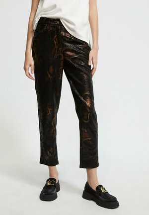 Black faux leather pants with a snake print pattern, featuring a shiny texture and relaxed fit, paired with chunky loafers.