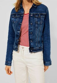 Dark blue denim jacket with button closures, two chest pockets, and light stitching details. Worn over a red and white striped shirt.