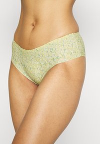 Fundo amarelo claro de biquíni feminino com um padrão floral em azul e verde. Tecido suave com uma textura lisa e cinta larga.