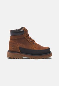 Botte de randonnée pour enfant en cuir marron et noir, avec lacets, col matelassé au niveau de la cheville, semelle texturée et logo Timberland sur le talon.