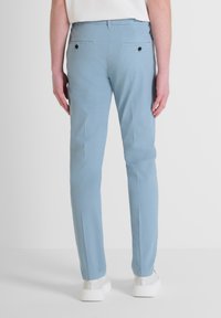 Svijetloplave hlače slim fit kroja, s dva stražnja džepa, crnim dugmadom kao detaljem i glatkimit, laganim materijalom.