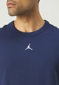 Marineblå bomulds T-shirt med rund hals, prydet med et hvidt Jumpman-logo på venstre brystområde. Blød tekstur og afslappet design.