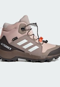 Ružičasta i siva poluvisoka planinarska čizma s teksturiranim gornjim dijelom, GORE-TEX oznakom, reflektirajućim naglascima i robusnim crnim potplatom.