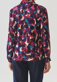 Blusa a maniche lunghe con motivo astratto colorato in rosa, blu e crema, dotata di colletto classico e polsini abbottonati. Tessuto morbido e leggero.