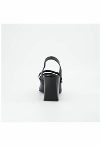 Sandales noires à talons avec une sangle à l'arrière et plusieurs fines sangles au niveau de la cheville. Le talon bloc haut présente une finition lisse.