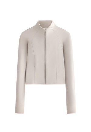 Světlý béžový kabát s dlouhými rukávy na zip, stojatým límcem a jemně texturovanou látkou, zobrazený na bílém pozadí.