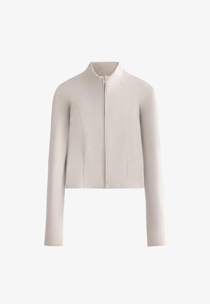 Světlý béžový kabát s dlouhými rukávy na zip, stojatým límcem a jemně texturovanou látkou, zobrazený na bílém pozadí.