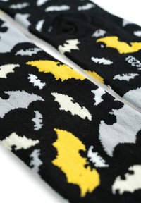 Calzini neri con un motivo a pipistrello in giallo, bianco e grigio. La trama lavorata a maglia è morbida e si allunga, adatta a varie misure di piede.