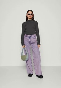 Langermet ribbet grå topp, avslappede lyse lilla jeans, svarte plattform sko og en liten grønn crossover-veske. Stilige solbriller fullfører antrekket.