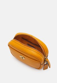 Žlutá kožená kosmetická taška s texturovaným povrchem, zlatými detaily, dvojitým zipem a vnitřní kapsou. Kompaktní a zaoblený design.