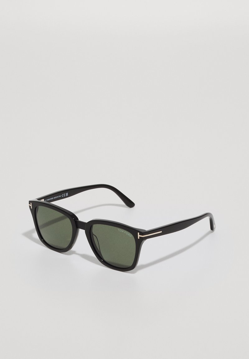 Black sunglasses with a geometric frame, dark green lenses, metallic accents on the temples, and textured matte finish.