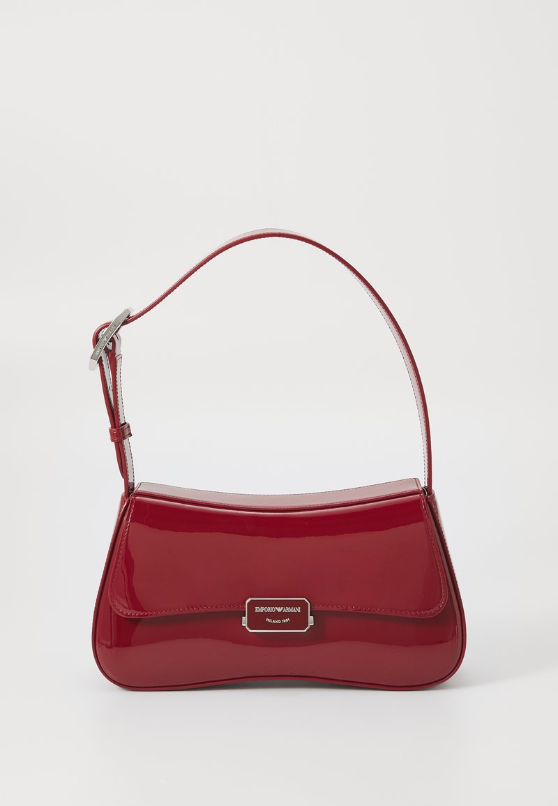 Borsa a tracolla in pelle verniciata rossa con design curvo, hardware silver e una breve tracolla regolabile. Presenta una placca con logo sulla parte anteriore.