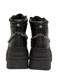 Stivaletti neri in pelle con una suola spessa, caratterizzati da dettagli in catena e linguette in tessuto. Finitura testurizzata e branding audace sul tallone.