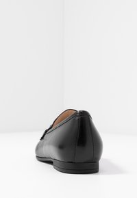 Svarta läderballerinas med låg häl, slät textur, spetsig tå och subtila sömnadsdetaljer. Mångsidig och minimalistisk design.