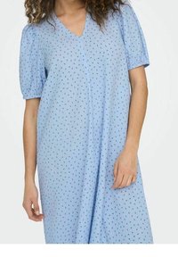 Vaaleansininen mekko, jossa on V-pääntie, lyhyet puffihihat ja pieniä vihreitä kukkakuoseja. Valmistettu pehmeästä kankaasta, jossa on virtaava ja löysä muotoilu.