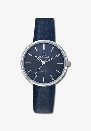 Montre quartz ronde avec un bracelet en cuir texturé bleu foncé, des éléments en métal argenté, et un cadran marine assorti avec des index horaires et le nom de la marque.