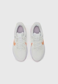 Baskets de sport gris clair avec un tissu texturé, logo Swoosh orange, semelles intérieures violettes et système de laçage traditionnel. Motif de semelle extérieure circulaire.