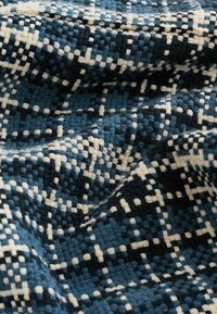 Textile featuring a woven pattern of dark blue, light blue, and cream squares, with a textured surface and soft, intertwined fibers.