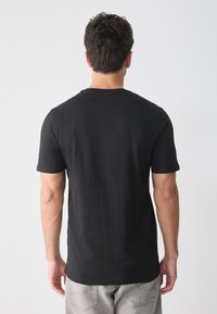 Schwarzes T-Shirt mit kurzen Ärmeln aus Baumwolle, mit Rundhalsausschnitt und glatter Textur, von hinten betrachtet.