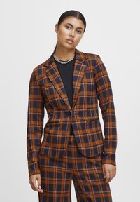 Rutet blazer i orange og navy med en tætsiddende design, enkeltknaplukning og klaplapper. Bukserne har et matchende mønster.