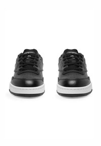 Čierne tenisky s hladkým koženým zvrškom, bielou gumovou podrážkou, perforovanými detailmi a čiernymi šnúrkami. Dvoje topánok smerujúcich dopredu.