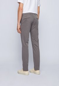 Grå chinos med en smal passform, utrustade med bakfickor, en slät yta och kombinerade med ljusa sneakers.