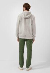 Jasnoszara teksturowana bluza z kapturem w komplecie z zielonymi spodniami. Bluza ma prążkowane mankiety i dół, a spodnie posiadają tylne kieszenie.
