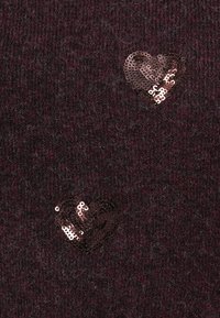 Dark burgundy knitted fabric with two sequin hearts in metallic rose gold. Textured surface with fine fibers and a soft appearance.