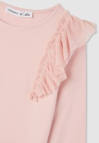 T-shirt rosa chiaro in cotone, con un'accortezza in tulle arricciato sulla spalla sinistra e un collo a giro. Etichetta per le istruzioni di cura attaccata.