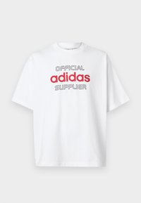 Bela majica s kratkimi rokavi z besedilom "URADNI dobavitelj adidas" v črni in rdeči barvi spredaj, okrogla vratna odprtina, enostavna podlaga.