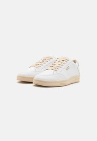 Weiße Leder-Sneaker mit beigen Schnürsenkeln und Sohle. Verfügt über eine abgerundete Zehenpartie und ein minimalistisches Design. Goldenes Logo-Detail an der Seite.
