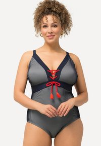 Costume da bagno intero a righe blu navy e bianche con scollatura a V profonda, dettagli in pizzo rosso con lacci e accentuazioni in contrasto con pompon. Spalline regolabili.