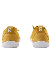 Gule ruskinds sneakers med en hvid gummisål, prydet med et struktureret design og et fremtrædende logo på hælflappen.