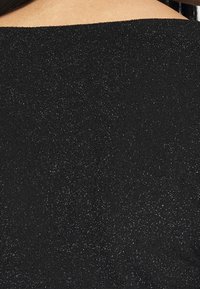 Svart topp med en texturerad, glittrande yta. Har en båtformad halsringning och ett mjukt, slätt tyg. Subtil glans tillför visuellt intresse.