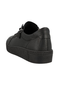 Sneaker en cuir noir avec une finition texturée, présentant un design bas, un rembourrage arrière et une semelle en caoutchouc avec des rainures verticales.