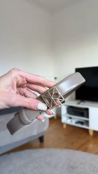 Cinturón de cuero beige con hebilla de acento geométrico dorado, textura suave y diseño elegante, sostenido sobre un fondo neutro.